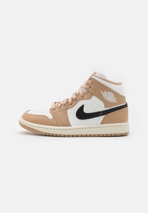Středně vysoké tenisky s béžovými a bílými koženými panely, černým Nike swoosh, béžovými tkaničkami a logem Air Jordan wings na kotníkovém límci.