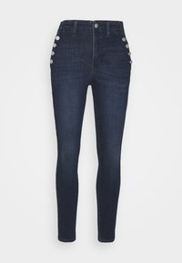 Mörkblå skinny jeans i denim, med fem knappar på vänster höft, hög midja och en slät yta.
