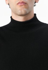 Maglione nero a collo alto realizzato in materiale a costine, con un design aderente, texture liscia e senza decorazioni visibili.