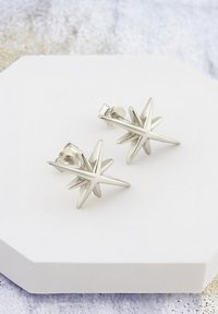 Silverfärgade stjärnformade studörhängen med en polerad finish, som har flera spetsiga accenter för en tredimensionell design.