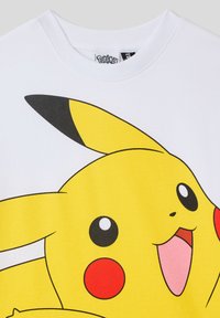 T-shirt bianco con una grande grafica colorata di Pikachu, con pelo giallo, guance rosa, orecchie con punte nere e una texture liscia.