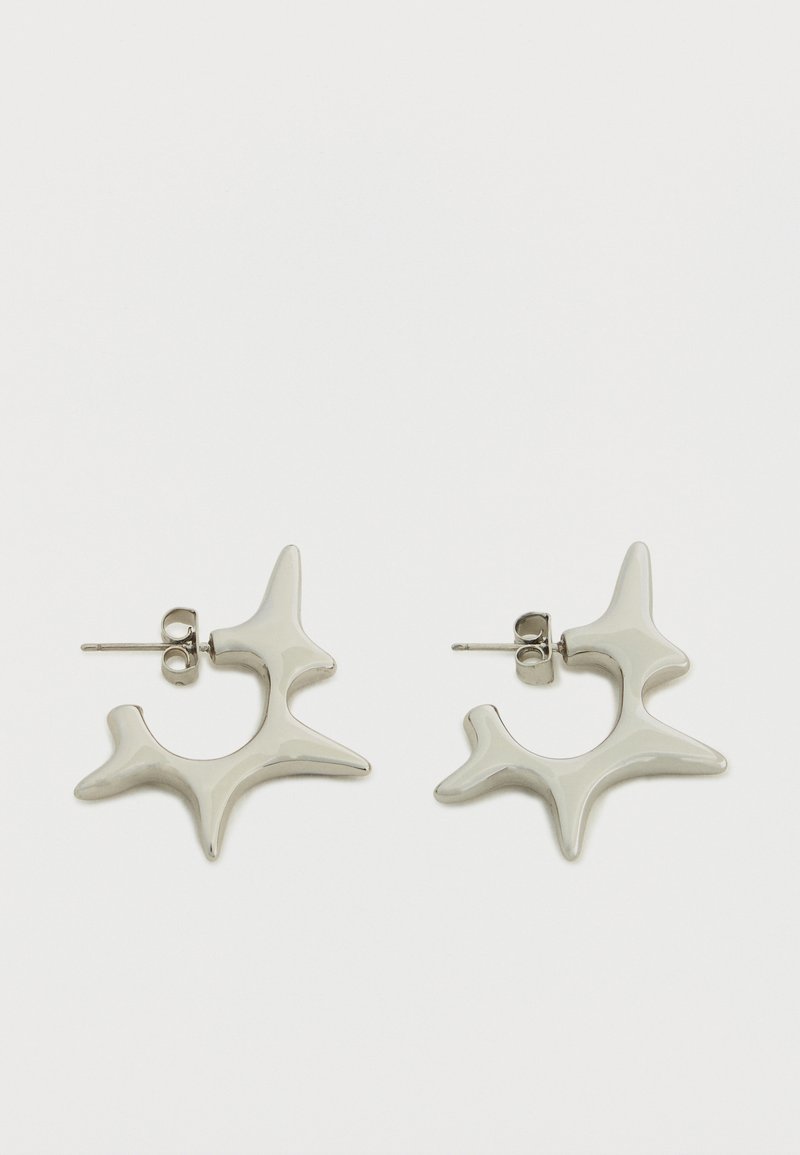 Ασημένια σκουλαρίκια με χαρακτηριστικό, αφηρημένο σχέδιο με ακανόνιστες μορφές και γυαλιστερό τελείωμα. Περιλαμβάνουν καρφάκι για στερέωση.