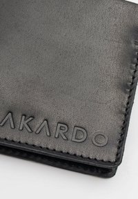 Portafoglio in pelle nera texture con logo embossato "AKARDO", con cuciture a vista lungo i bordi, che presenta un design elegante.