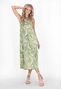 Rochie maxi cu imprimeu paisley verde, având decolteu tip keyhole și material fluid. Asortată cu sandale cu talpă joasă bej deschis.