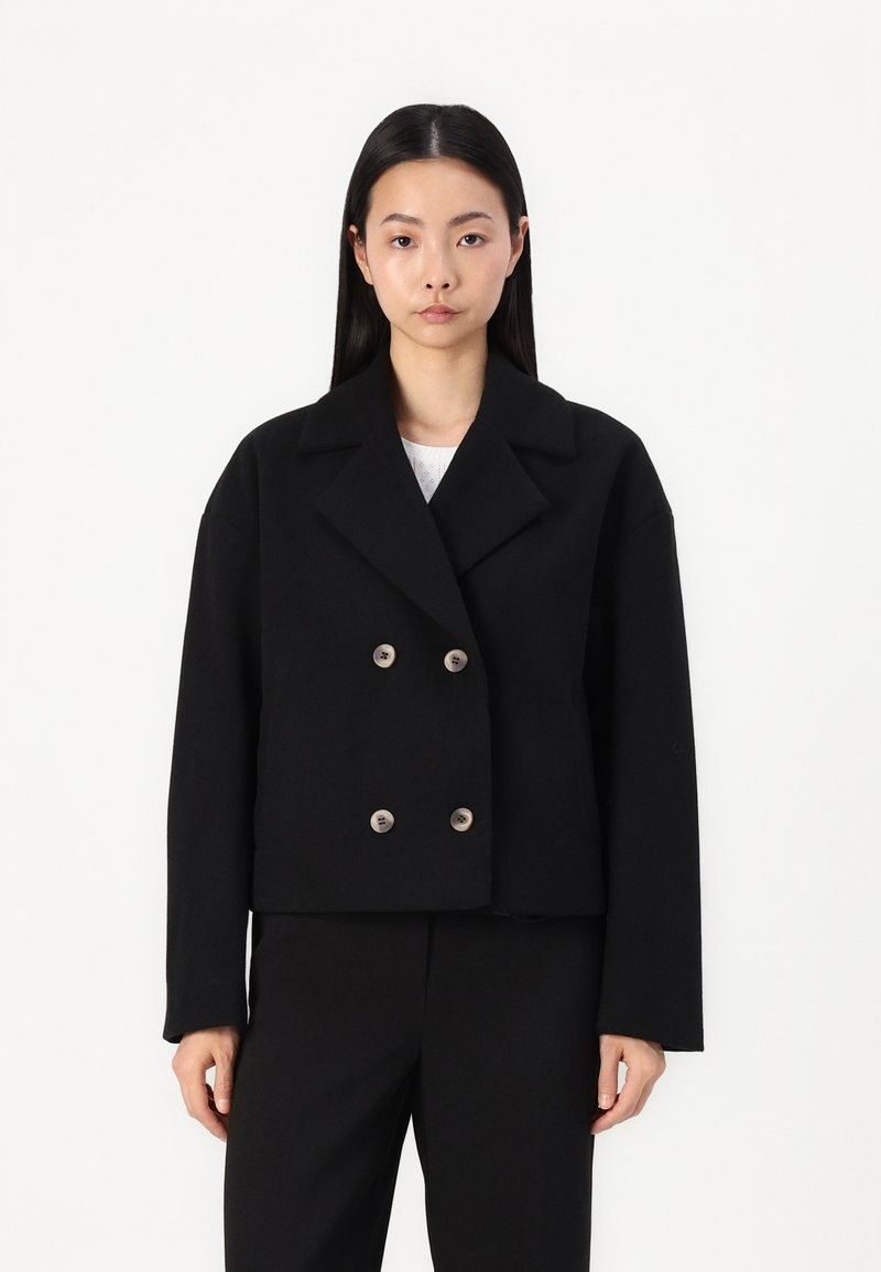 Black cropped blazer with a double-breasted front, broad collar, and silver-tone buttons; made of a thick fabric for structured shape.