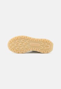 Rubber outsole with a textured pattern and deep treads. Light beige color with prominent herringbone design for traction.