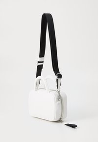Borsa a mano rettangolare bianca in pelle con doppi manici, chiusura con zip e tracolla nera removibile con dettagli in metallo argentato.