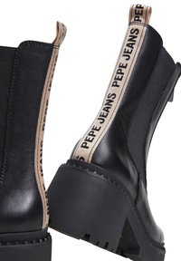 Černé kožené kotníkové boty s texturovanou elastickou stranou a hnědým textilním poutkem se značkovým nápisem "PEPE JEANS". Silná podrážka.