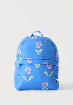 Sac à dos bleu avec motif de fleur violette et feuille verte, poche avant zippée et poignée supérieure sur fond neutre.
