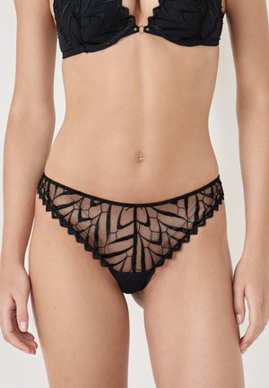 Black lingerie set with a sheer mesh front, featuring a floral pattern, scalloped edges, and a solid black back.