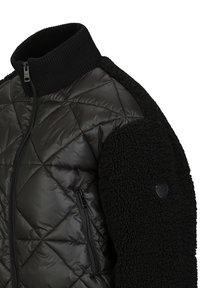 Gequilted zwarte pufferjas met een geribbelde kraag, pluizige zwarte fleece mouwen, zijzak met rits en een logo op de linker schouder.