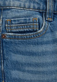 Modra džins tkanina z majhnim sprednjim žepom, kontrastnim rumenim šivom in kovinskim gumbom z rustikalnim zaključkom.