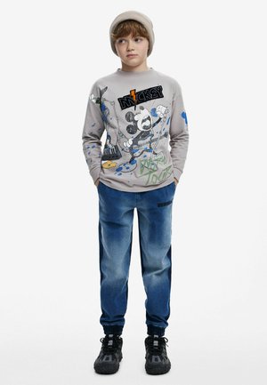 Gray long-sleeve shirt with Mickey Mouse graphic, featuring blue paint splatters. Blue jeans with side stripes, elastic cuffs, and dark sneakers.
