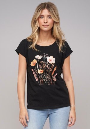 Svart T-skjorte i bomull med et blomsterdesign i oransje, rosa og kremfarge, rullet korte ermer og rund hals.