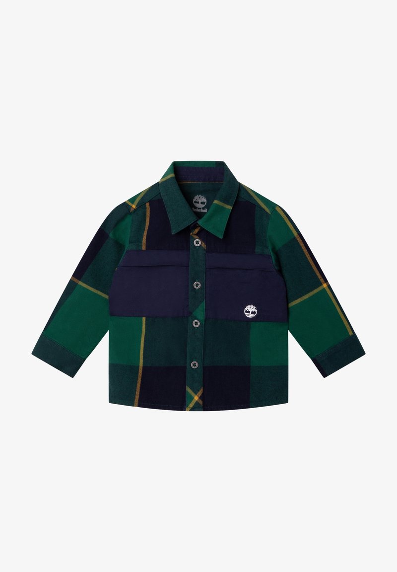 Ruudullinen paita vihreällä, laivastonsinisellä ja keltaisella värillä; siinä on pitkät hihat, napitus edessä sekä rintatasku, jossa on logo-patch.
