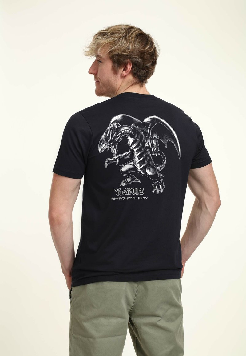 Camiseta de algodón negra con un detallado gráfico gris de un dragón en la parte posterior. Diseño de mangas cortas y cuello redondo.