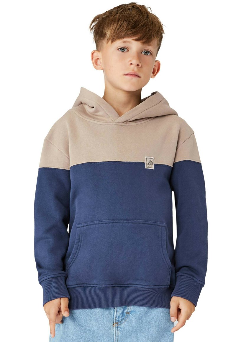 Hoodie i beige och marinblå. Har en kängeru ficka, ribbade ärmar och en tygpatch-logotyp på bröstet. Mjuk, strukturerad material.