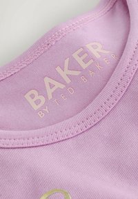 Gros plan sur un col en tissu côtelé rose avec l'inscription "BAKER BY TED BAKER" en rose pâle à l'intérieur du col.