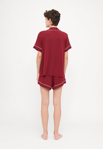 Μαρόν σετ πιτζάμας από μαλακό ύφασμα; το πουκάμισο έχει γιακά και κοντά μανίκια, ενώ οι σορτς διαθέτουν λευκή ραφή κατά μήκος του στριφώματος.