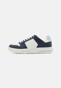 Navy blue and white sneaker featuring leather uppers, perforated toe design, textured side panels, and a textured white rubber sole.
