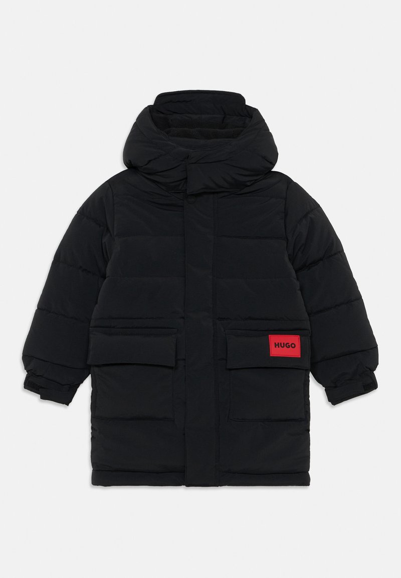 Must mustaga, millel on kõrge krae, kaks esikotti ja erksavärviline punane silt, millel on kirjas "HUGO." Tekstuuriga isoleeritud disain.