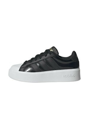 Sneaker nera bassa con suola bianca spessa, lacci neri e tre strisce nere sul lato.