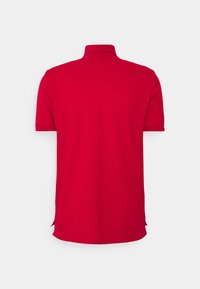 Polo rouge à manches courtes, avec col et fentes sur les côtés pour plus de liberté de mouvement. Fabriqué en tissu lisse et respirant.