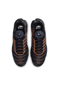Baskets de sport noires avec des accents orange, en matériau en maille, de forme arrondie, semelle noire épaisse et un système de laçage bien visible. Détail de logo remarquable sur la languette.