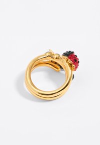 Gold-tone ring with three intertwined bands, featuring a ladybug design in red, black, and yellow accents on top. Glossy finish.