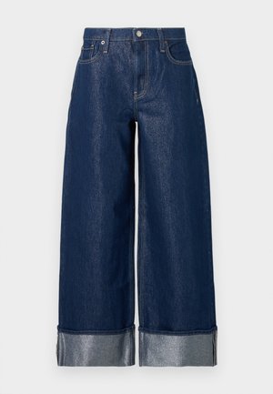 Vide benfargede jeans med høy midje, fem-lommers design og brettede mansjetter som viser lysere indre stoff.
