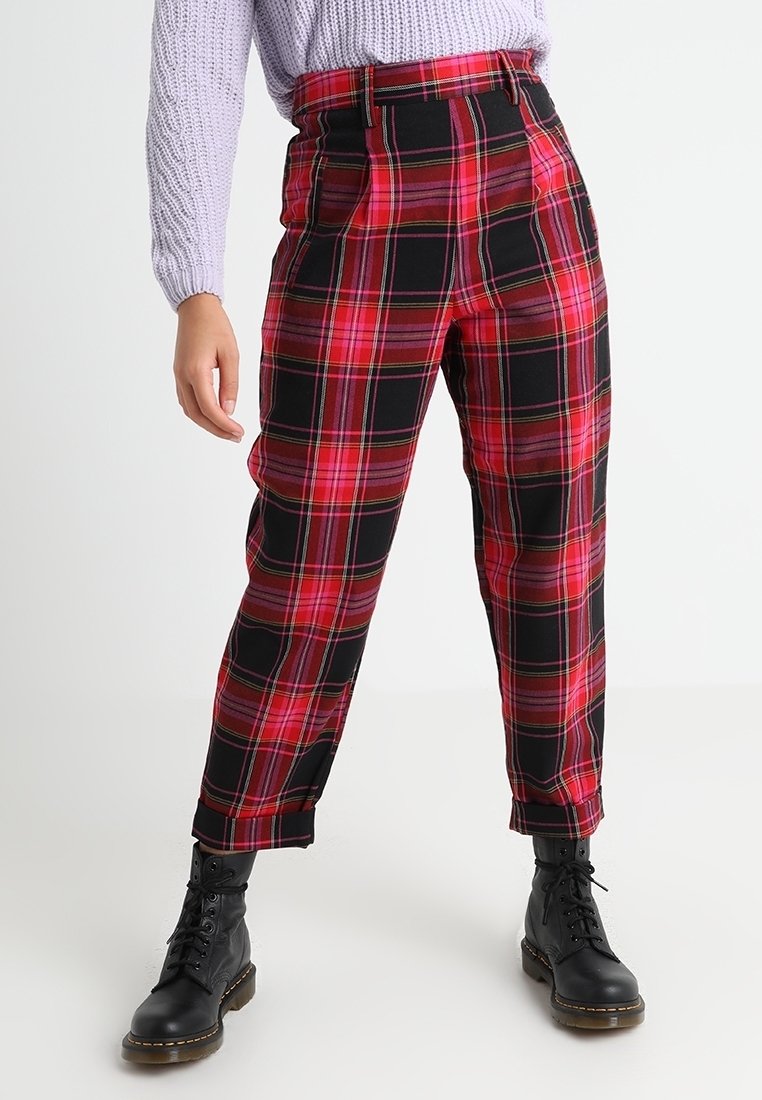 Röda och svarta rutiga byxor med hög midja, avsmalnande ben och frontveck. Bärs med svarta snörstövlar och en ljuslila tröja.