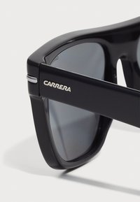 Sorte plaststøygler med mørke linser, med rektangulær ramme og sølvfarget "CARRERA"-logo på siden. Elegante linjer med glatt tekstur.