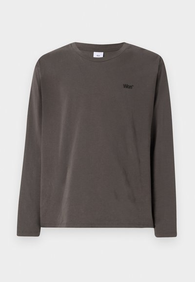 Hosszú ujjú, sötétszürke pamut ing, kerek nyakkivágással és egy kis fekete logóval a bal mellrészen. Simaság jellemzi, laza dizájnnal.