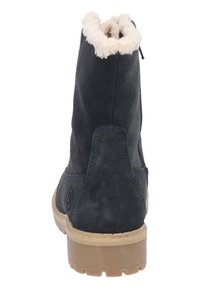 Botines de ante azul oscuro con un cuello de falso pelo y una suela de goma texturizada, con un detalle de logo en el lateral.