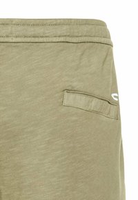 Olivenfarvede shorts lavet af blød, struktureret stof. Har en baglomme med en simpel klap, hvilket tilføjer funktionel detalje.