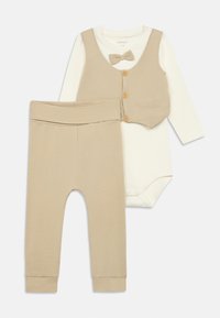 Beige csecsemő öltözet, amely hosszú ujjú fehér bodyból, bézs mellényből fából készült gombokkal és hozzá illő bézs leggingsből áll.