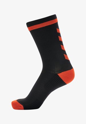 Zwarte sok met oranje accenten. Heeft een geribbelde structuur, egaal kleurontwerp en een verstevigde teen. Verticale oranje strepen aan de zijkant.