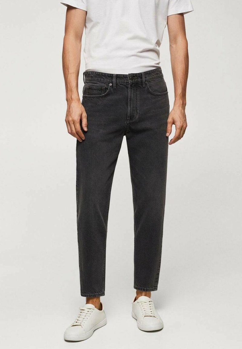 Jeans en denim noir avec une coupe droite, dotés d'un design à cinq poches, de détails cousus et d'un ourlet légèrement raccourci, assortis à des baskets blanches.