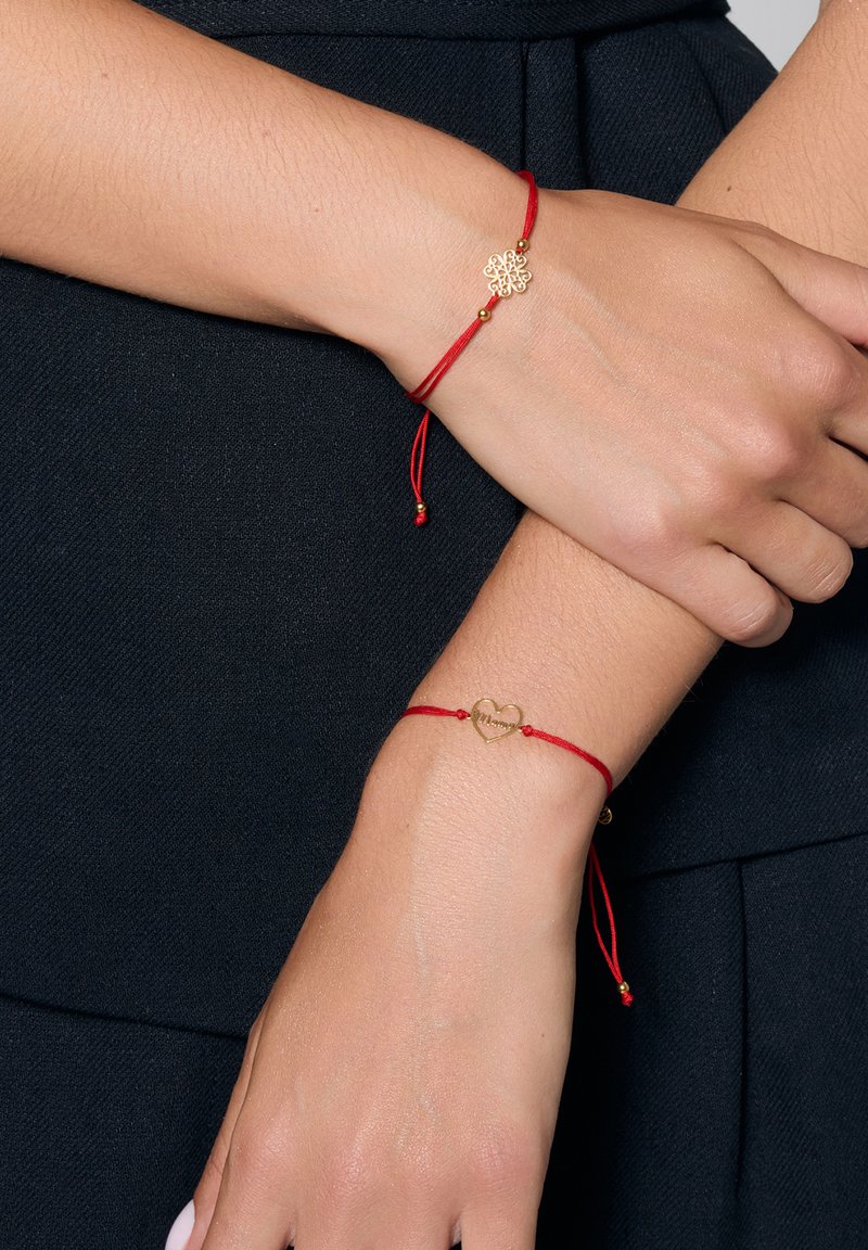 Dwie czerwone bransoletki z cordu z złotym wykończeniem. Jedna ma wzór kwiatowy, a druga w kształcie serca z wygrawerowanym napisem "Mama".