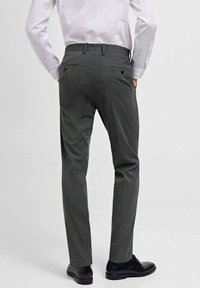 Pantaloni gri asortați, cu o textură netedă, având două buzunare pe spate și un design cu picior dreapt, asortați cu pantofi negri.
