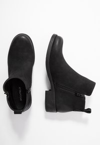 Černé kotníkové boty s texturovaným semisovém povrchem, postranním zipem pro zapínání a nízkým blokovým podpatkem. Obsahují poutko pro snadné obutí.