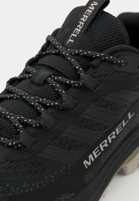 Czarne sportowe buty z siateczki i materiału syntetycznego, z teksturowaną cholewką, kontrastowymi sznurówkami oraz logo Merrell na boku.