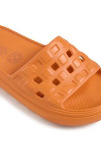 Orange slide sandal gjord av strukturerad gummi. Har ett rutmönster på remmen, med en platt sula och lätt kurva för komfort.