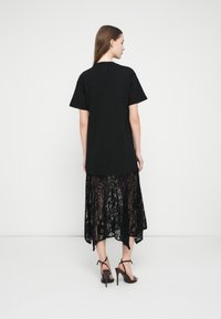 Juoda trumpomis rankovėmis marškinėliai sluoksniuojami su juoda nėrinių suknele, kurioje yra rožinė apačia. Dėvimi su aukštu kulnu sandalais su dirželiais.