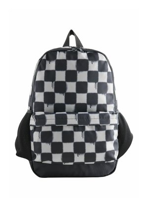 Sac à dos avec motif à carreaux noir et blanc présentant des formes carrées irrégulières avec des gouttes de peinture, poche avant zippée et poches latérales en mesh.