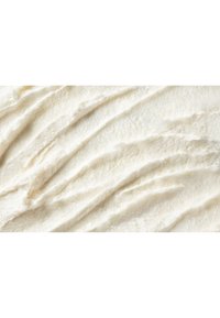 Superficie cremosa e strutturata di glassa bianca con leggere rientranze e zone lisce, che mostra una lucentezza brillante e un aspetto morbido.