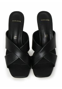 Sandali in pelle nera con fascette incrociate e punta quadrata. Presentano una superficie liscia e un marchio dorato sulla soletta.