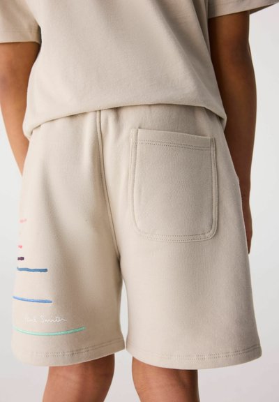 Beige shorts i mjukt material, med en bakficka, färgglada broderade ränder och en logotyp nära fållen.
