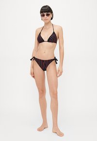 Schwarzes Bikini-Set mit einem dreieckigen Oberteil und gebundenen Seitenbündchen, verziert mit fettem roten Text. Glattes Gewebe mit passgenauem Design.