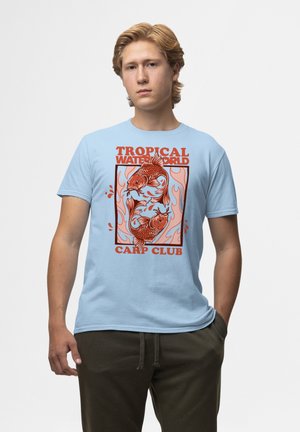 Světlemodré bavlněné tričko s grafikou dvou oranžových kaprů v rámci, s textem "TROPICAL WATER WORLD" a "CARP CLUB" pod nimi.